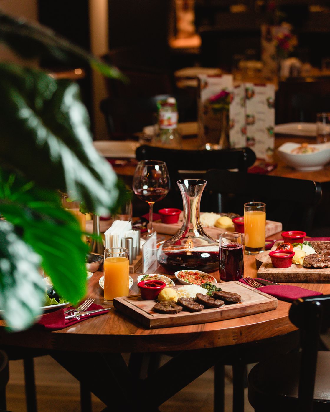 A restaurant table set with grilled dishes, juice and a wine decanter